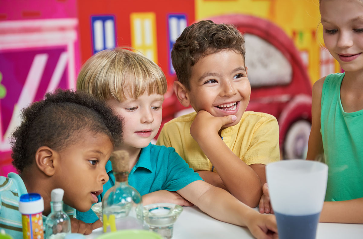 Happy children seated in front of science equipment.
